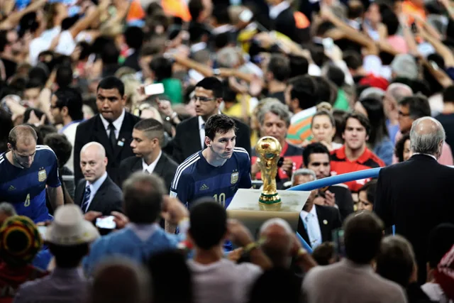 Lionel Messi walking past the World Cup trophy